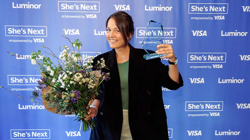 smiling woman holding flowers and shes next award